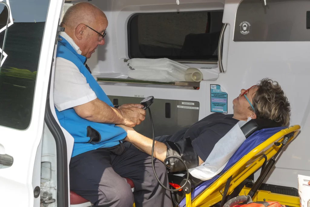 Ambulancier prenant la tension d'un patient allongé dans une ambulance.