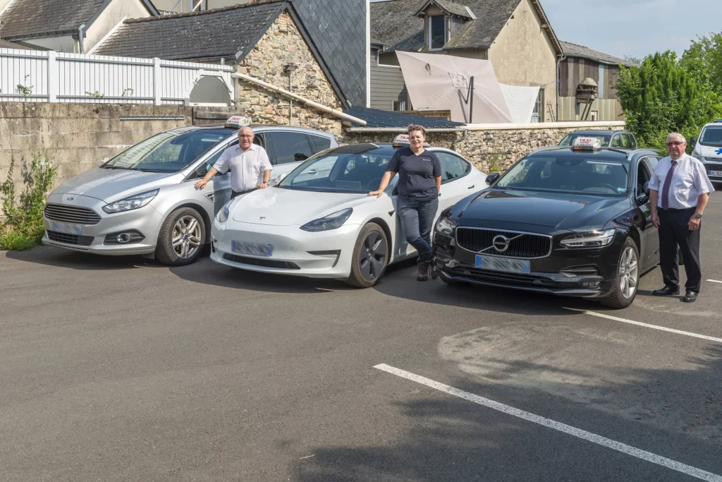 Chauffeurs de taxi et ambulanciers posant devant leur flotte de véhicules.